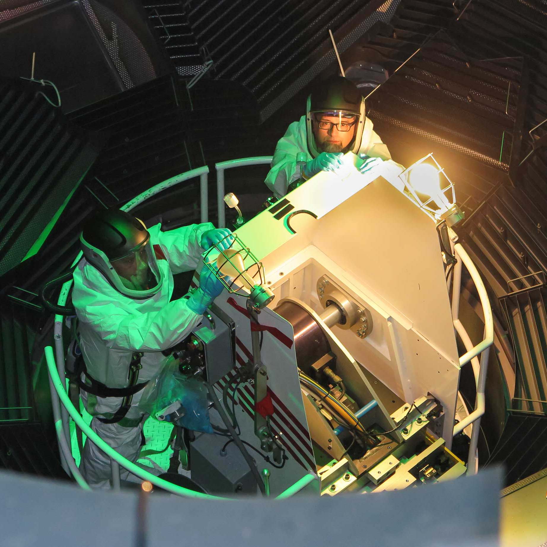 Two service technicians of PAR Systems in body suits on a manlift in a nuclear environment