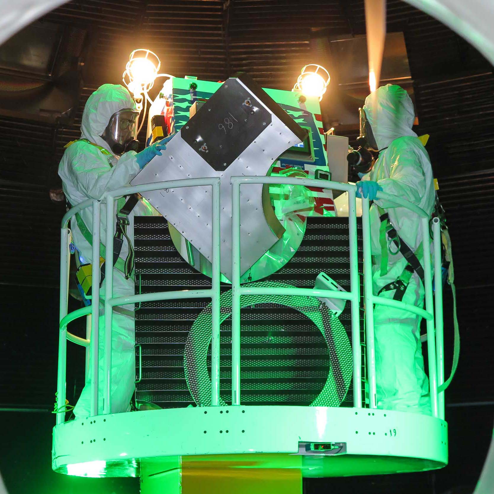 Two service technicians of PAR Systems in body suits on a manlift in a nuclear environment