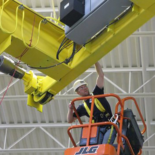 Maintenance man in a suspended man basket applying a crane update.